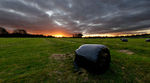 Sunset and black plastic wrapped haybale