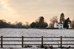 Snowy field and white house at sunset