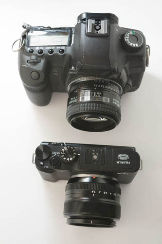 Canon 5D Mk II DSLR camera with Nikon 50mm f/1.4 lens compared in size to Fuji X-A1 Mirrorless Camera with Fuji 35mm f/1.4 lens (top down view)