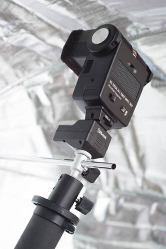 Mini ballhead umbrella holder in use, attached to monopod with umbrella inserted through umbrella slot, and wireless flash trigger with flash attached on top