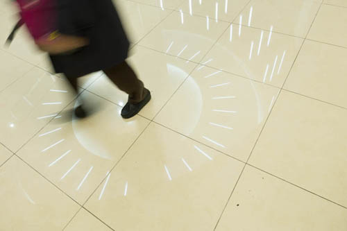 Feet of someone walking across the reflection of ceiling lights inside Gwangju bus terminal