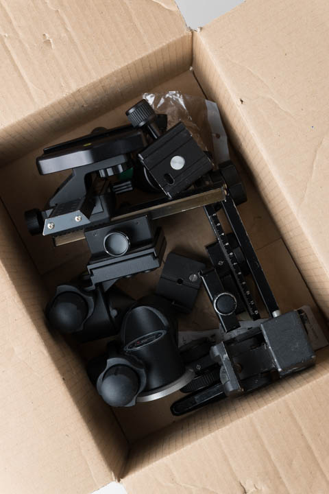 Tripod heads in a cardboard box, not arranged in any fashion other than to fit them in the box