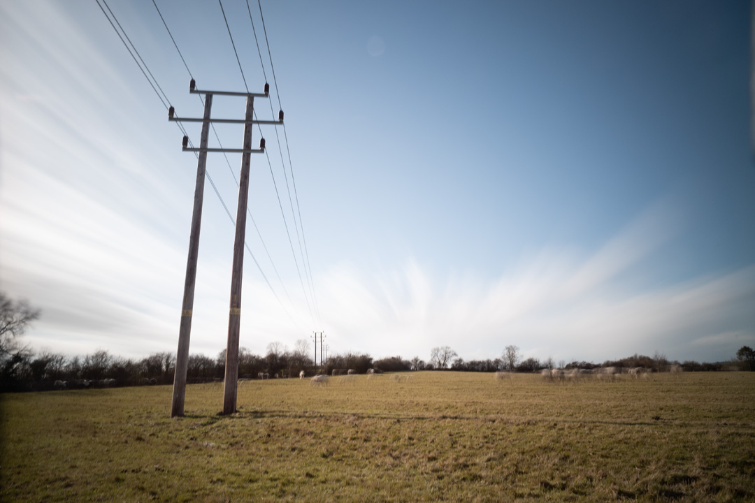 Photo of power lines crossing a field taken on a standard Fuji X-A1 camera with Schott BG40 IR cut filter, XCSource 10 stop glass ND filter and Hitech 1, 2, and 3 stop plastic ND filters