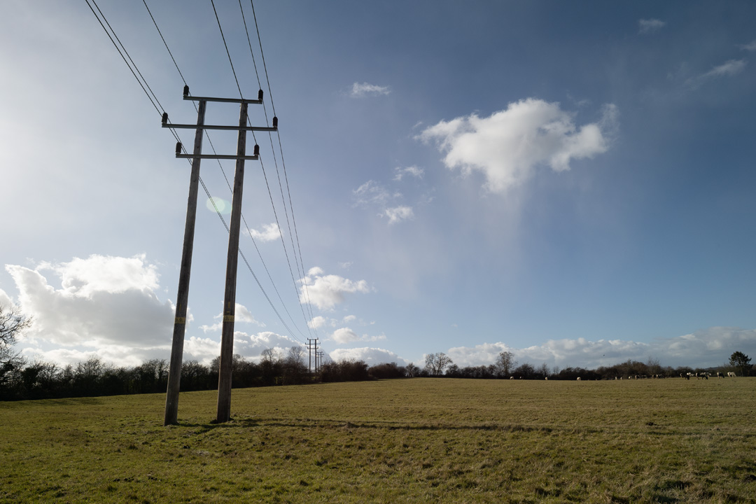 Photo of power lines crossing a field taken on a standard Fuji X-A1 camera with a wide-angle lens with Schott BG40 filter