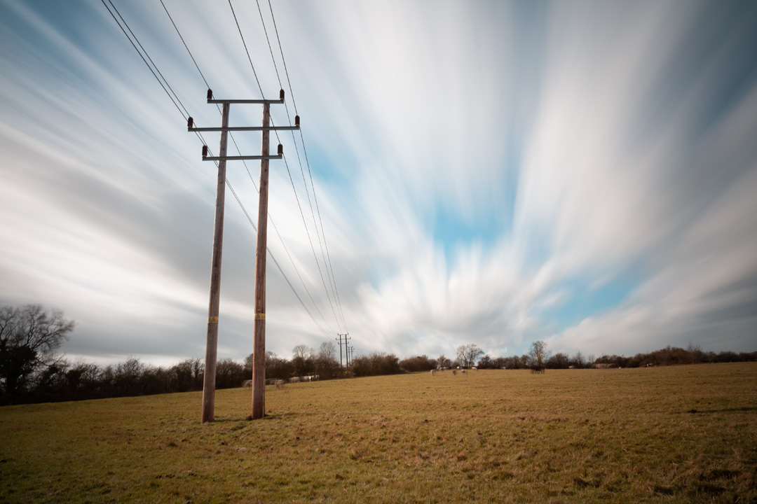 Photo of power lines crossing a field taken on a standard Fuji X-A1 camera with a wide-angle lens with XCSource 10 stop glass ND filter and Hitech 1, 2, and 3 stop plastic ND filters