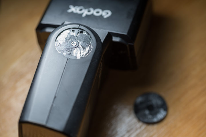 Hinge screw normally hidden under rubber cover on Godox TT350 flash