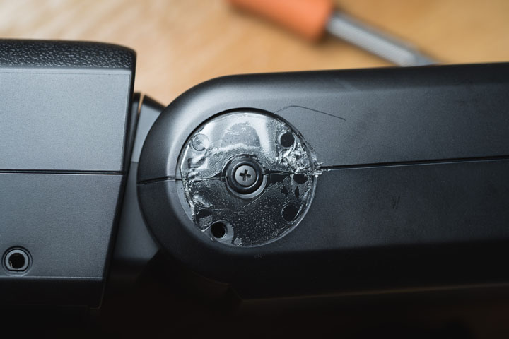 Godox V480 flash with rubber cover removed from the side of the hinge, revealing screw