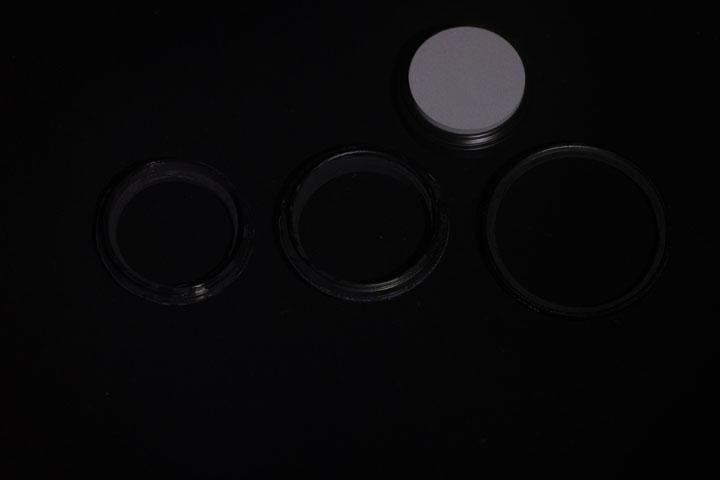 Photo of filter rings after painting with Black 2.0 paint, shot in ultraviolet light