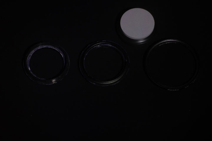 Photo of filter rings before painting with Black 2.0 paint, shot in ultraviolet light