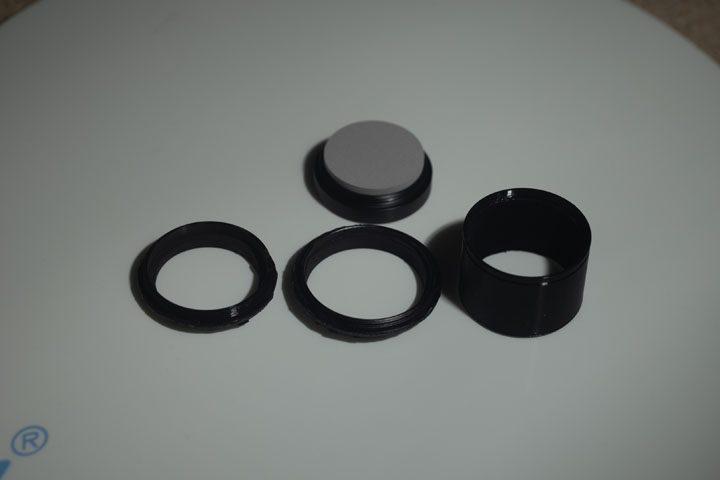 Photo of filter rings after painting with Black 2.0 paint and an unpainted 3D printed PTEG lens hood, shot in visible light with a white background